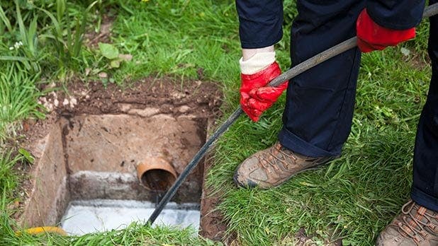 Person working on a sewer system in grass