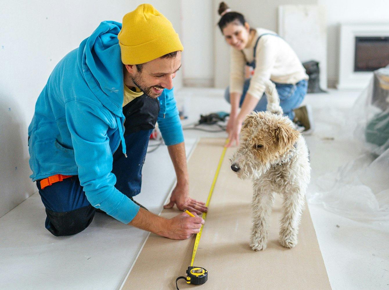 a couple working on a home renovation project while their dog looks on