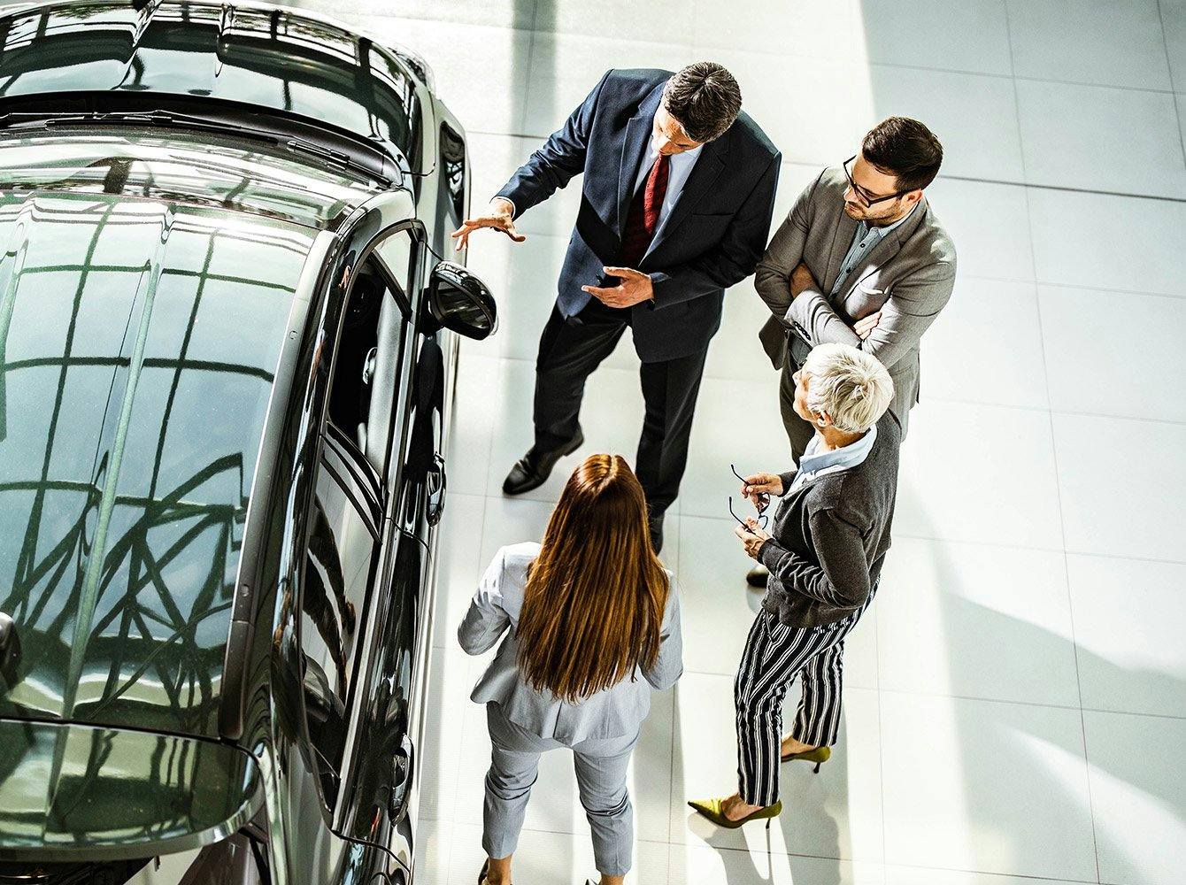 people at an auto dealership looking at a car for sale