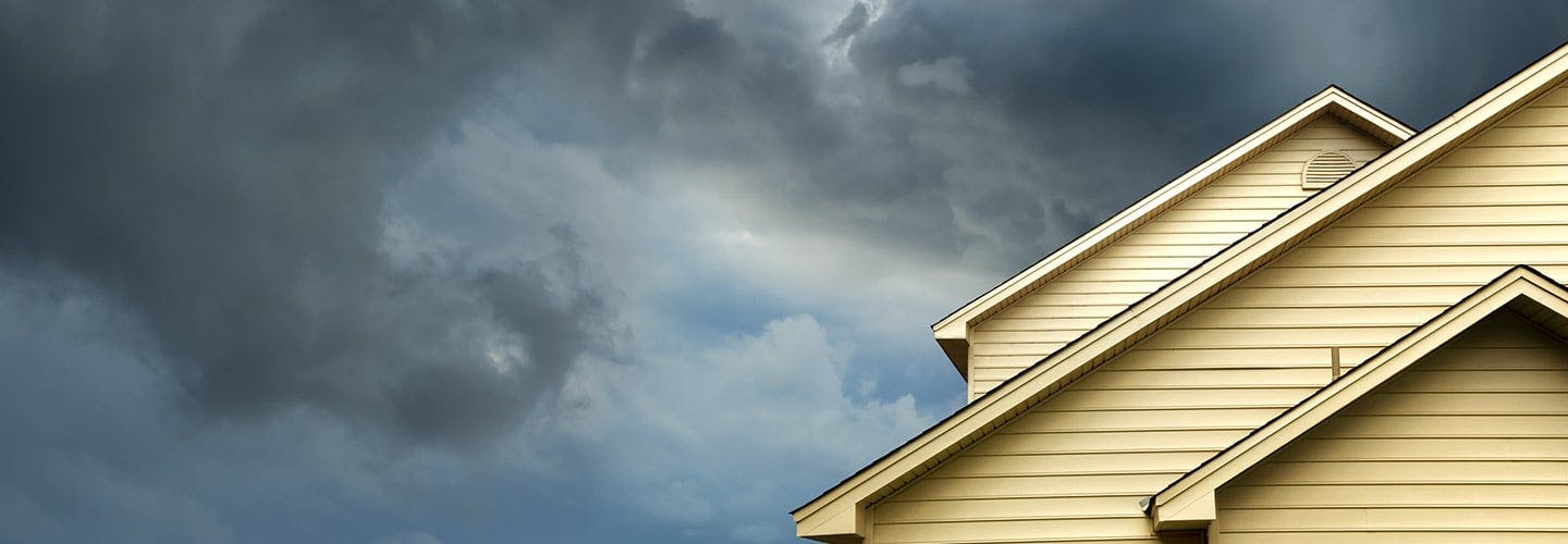 top of a house with dark storm clouds in the sky behind it