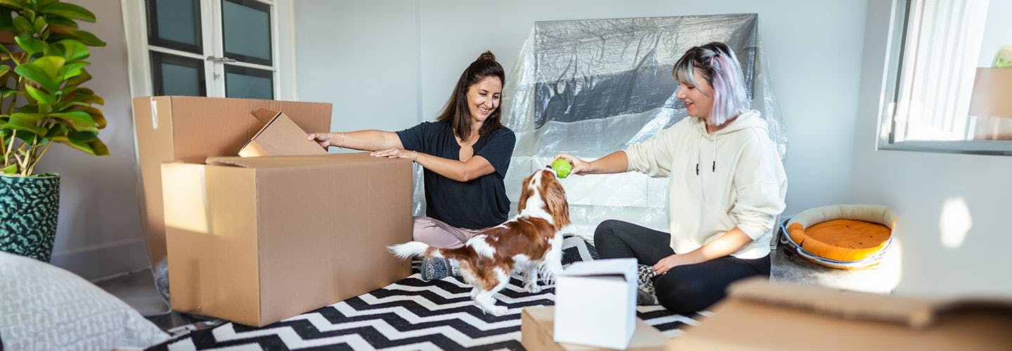 two women unpacking and playing with a dog