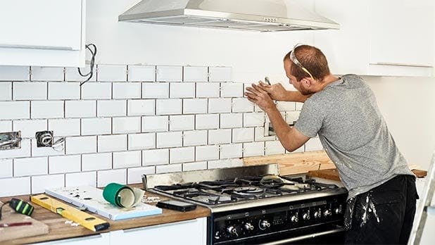 Man adding new tile to kitchen wall 