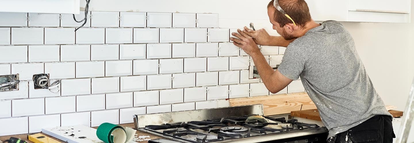 Man adding new tile to kitchen wall 