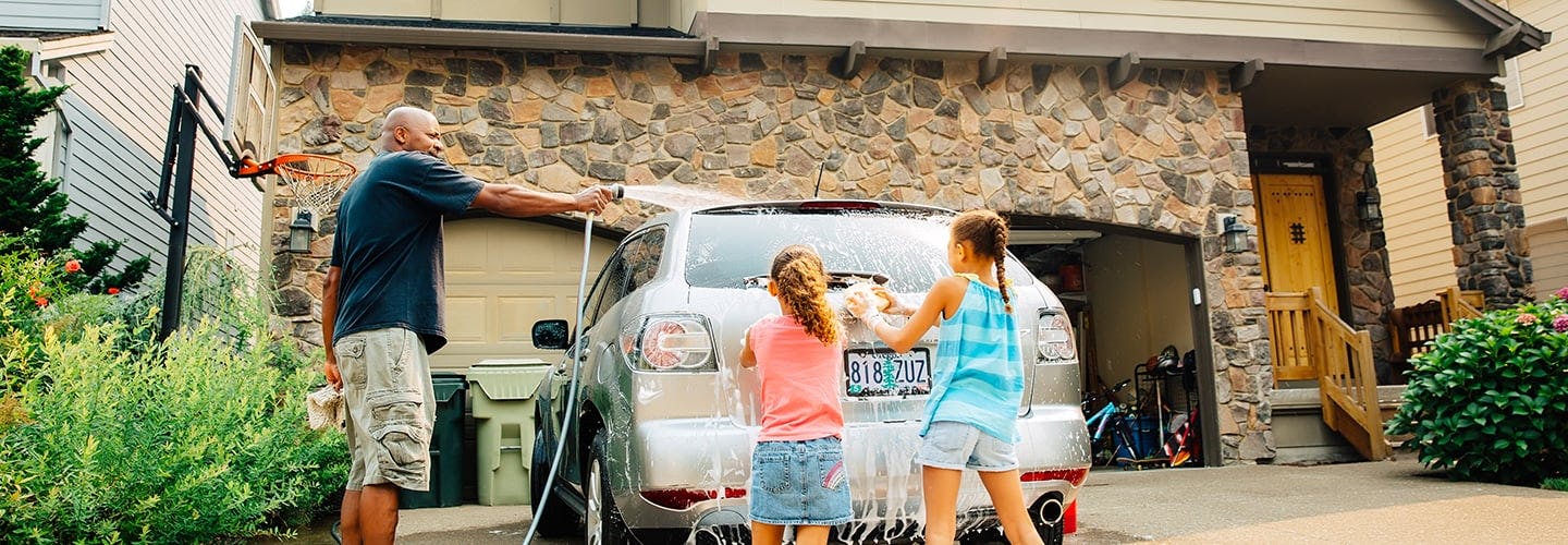 family washing a car together in the driveway