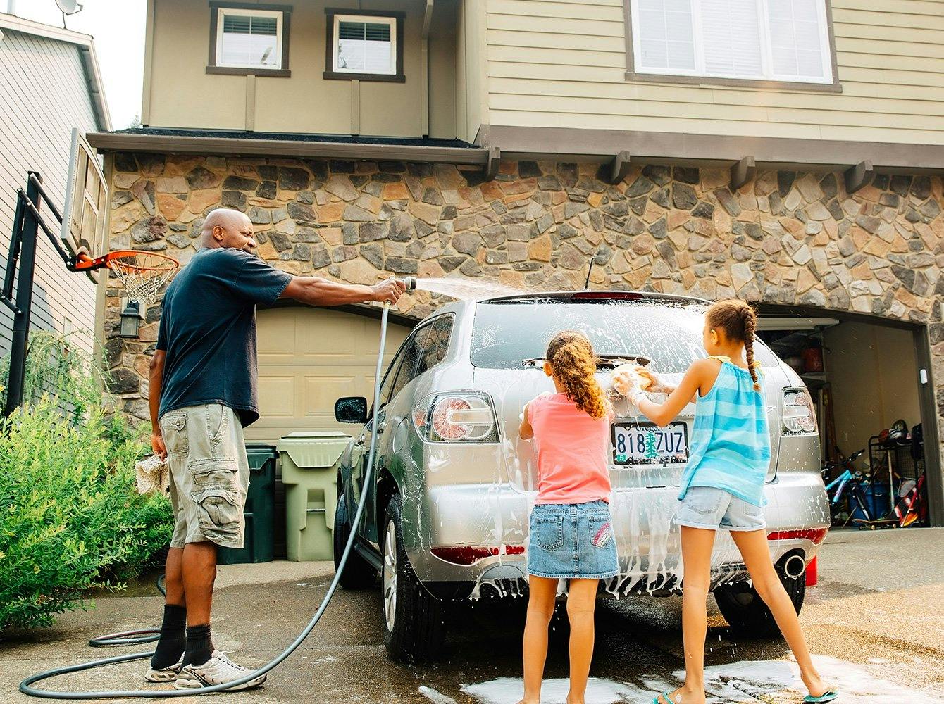 family washing a car together in the driveway