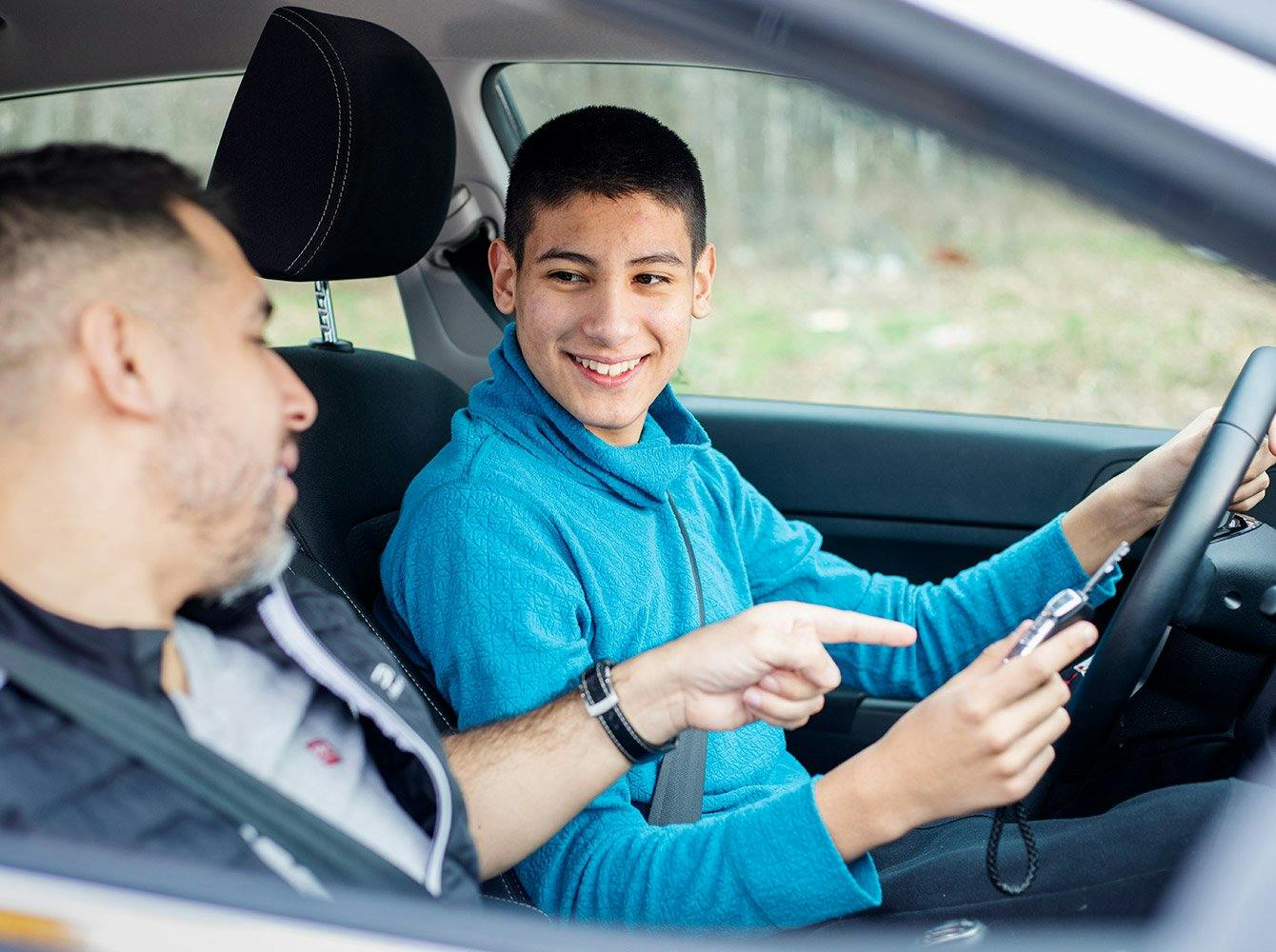 teenager learning to drive with an adult in the passenger seat