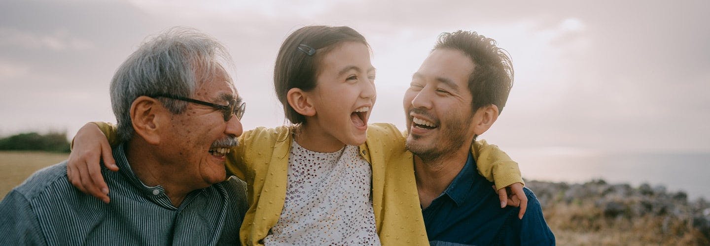 young girl has her arms around father and grandfather all smiling