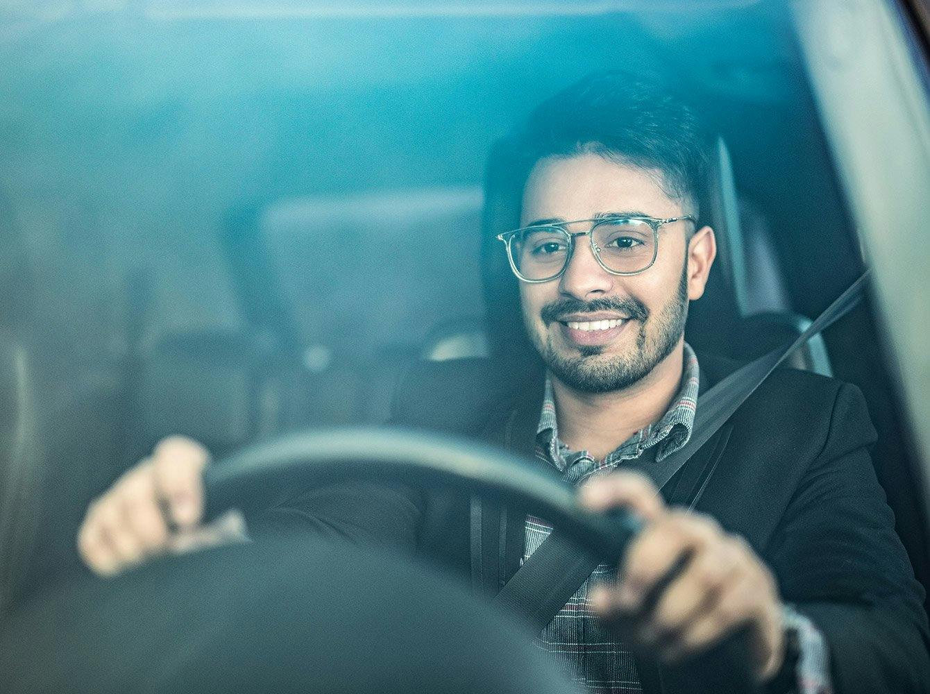 smiling man with his hands on a steering wheel