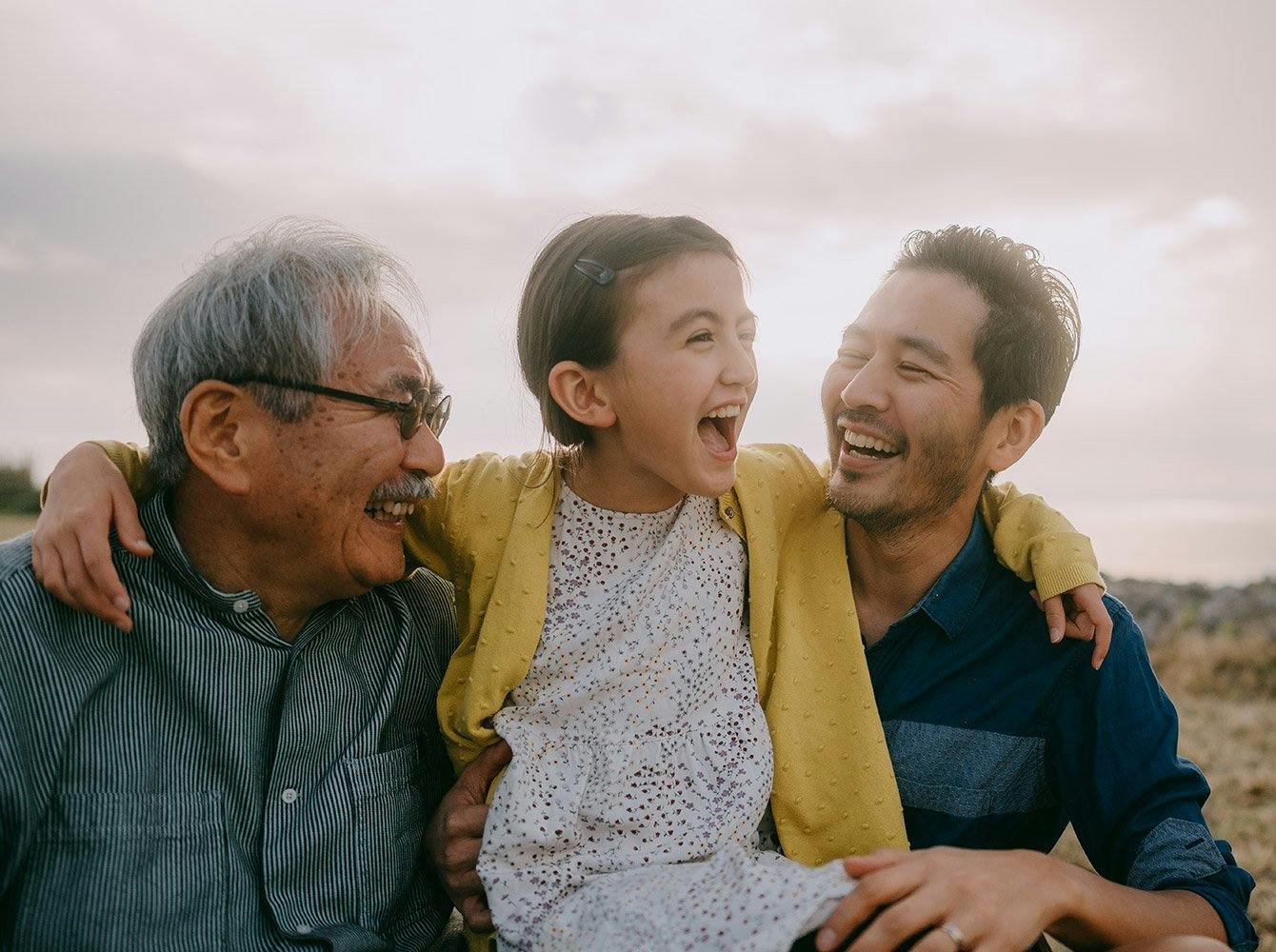 young girl has her arms around father and grandfather all smiling