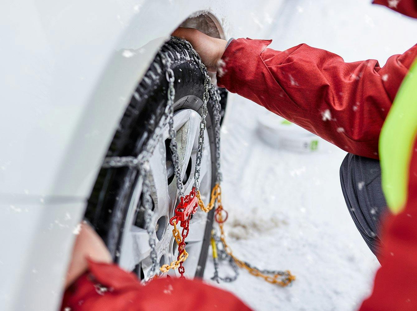 close up of someone putting chains on their car tires in the winter